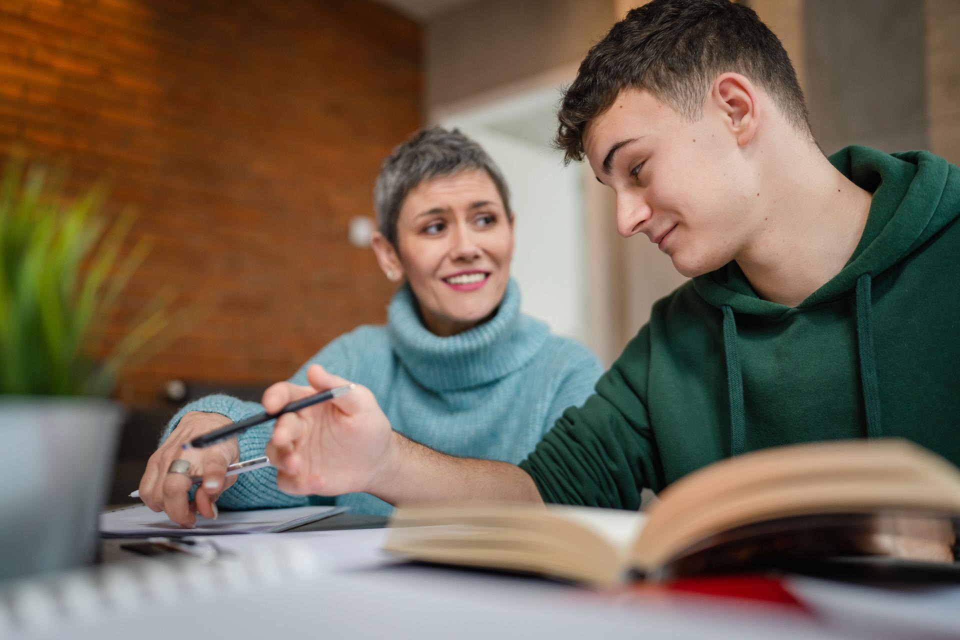 One student teenage caucasian man study learn with help of his tutor professor or mother senior woman at home having private lesson to prepare for exam education concept real people copy space